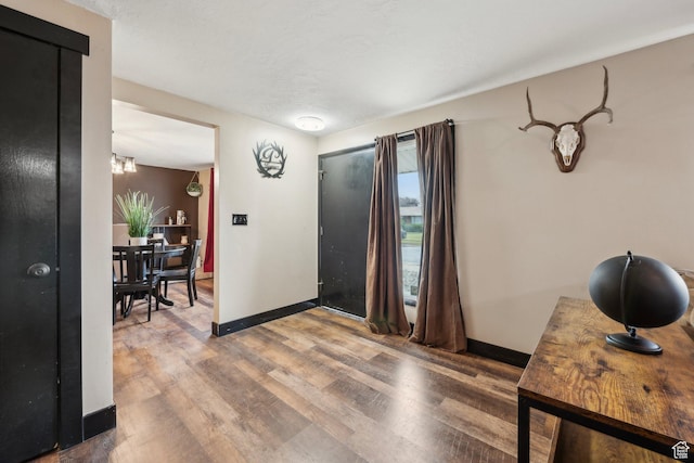 foyer with wood finished floors, baseboards, and a chandelier