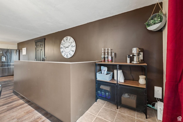 bar featuring stainless steel fridge with ice dispenser and wood finished floors