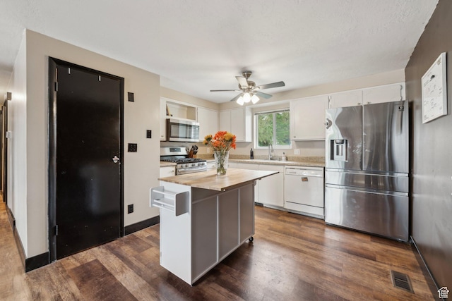 kitchen featuring appliances with stainless steel finishes, white cabinetry, a ceiling fan, dark wood-style floors, and butcher block counters