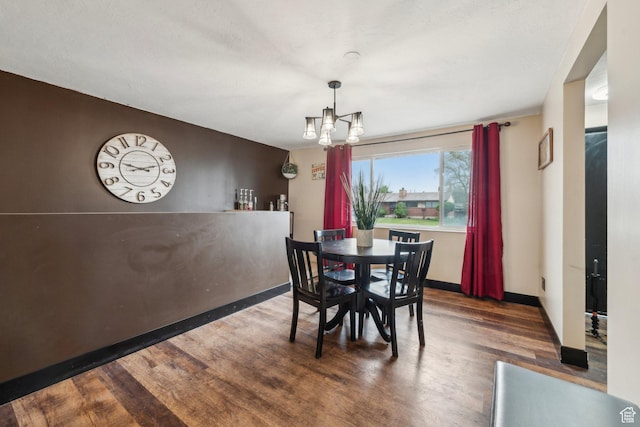 dining space featuring wood finished floors, a chandelier, and baseboards