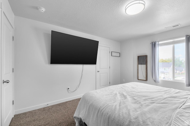 bedroom with a textured ceiling, carpet flooring, and baseboards