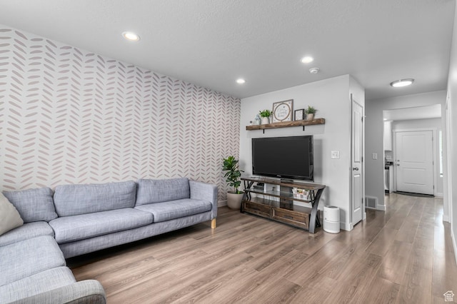 living room featuring an accent wall, wallpapered walls, recessed lighting, light wood-style flooring, and baseboards