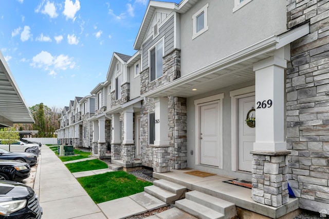 property entrance with stone siding, stucco siding, and a residential view