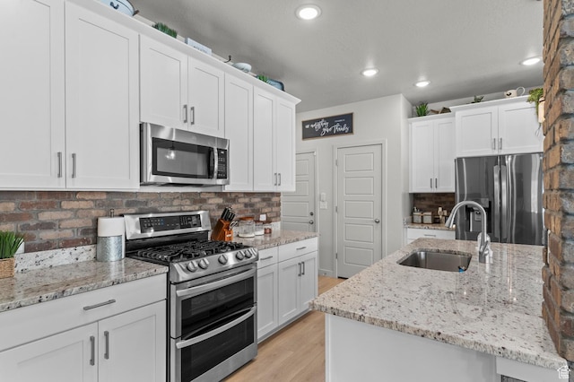 2546 N Wister Ln Unit 334, Lehi, UT 84043 - kitchen featuring stainless steel appliances, a sink, light wood-style flooring, decorative backsplash, and white cabinetry