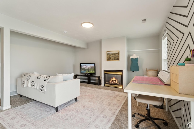 carpeted home office featuring a glass covered fireplace
