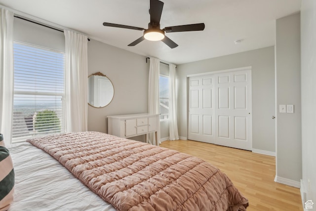 bedroom with wood finished floors, baseboards, a closet, and ceiling fan