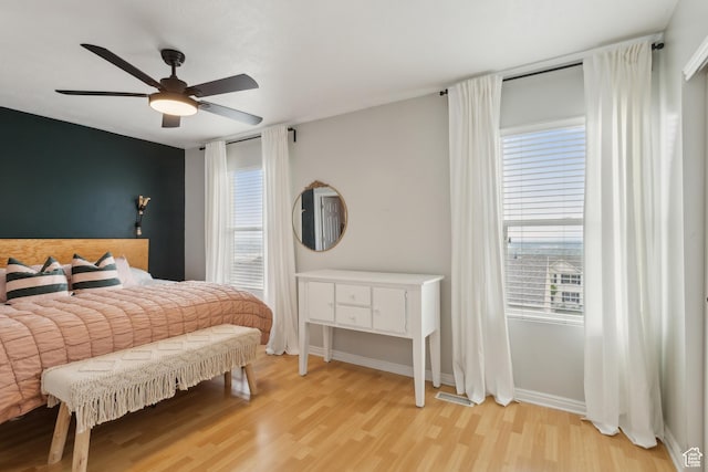 bedroom with wood finished floors, multiple windows, ceiling fan, and baseboards