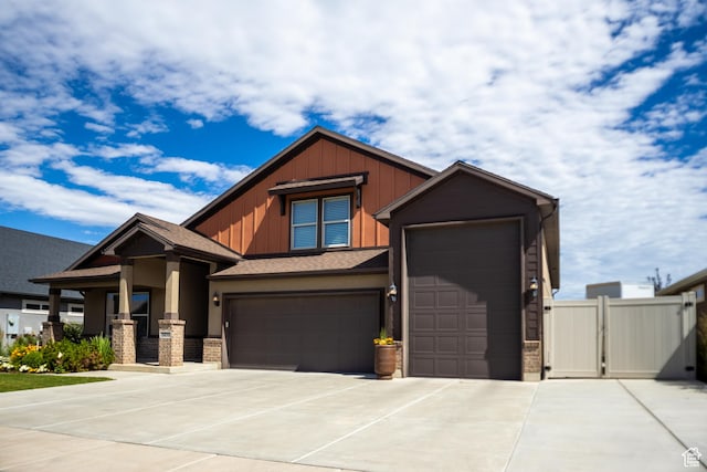craftsman-style house featuring driveway, a gate, board and batten siding, an attached garage, and fence