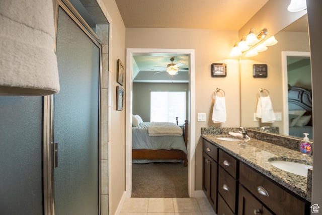 ensuite bathroom featuring a ceiling fan, a stall shower, tile patterned flooring, double vanity, and baseboards