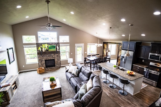 carpeted living area featuring recessed lighting, a ceiling fan, a fireplace, baseboards, and high vaulted ceiling