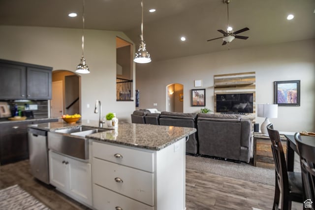 kitchen featuring arched walkways, a ceiling fan, stainless steel dishwasher, a sink, and high vaulted ceiling