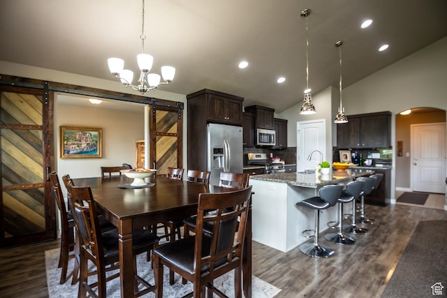 dining area with a barn door, arched walkways, dark wood-style flooring, lofted ceiling, and recessed lighting