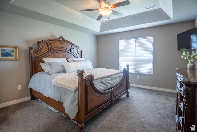 carpeted bedroom featuring a tray ceiling, baseboards, and ceiling fan