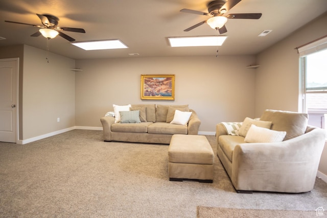 carpeted living area with a skylight, ceiling fan, and baseboards
