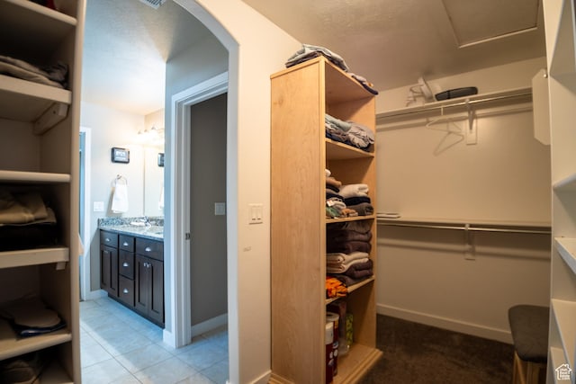 walk in closet with arched walkways and light tile patterned floors