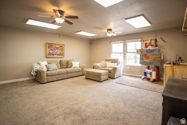 carpeted living area featuring a ceiling fan, baseboards, and a skylight