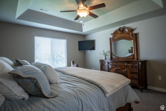 bedroom with a raised ceiling, carpet, baseboards, and ceiling fan