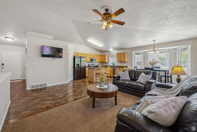 living area with ceiling fan, baseboards, a textured ceiling, lofted ceiling, and a chandelier