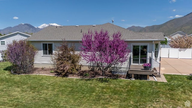 back of house with a mountain view, roof with shingles, and a patio