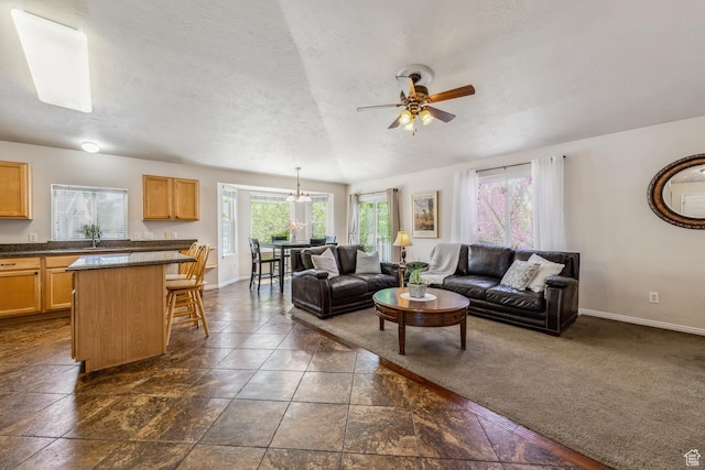 living area with a ceiling fan, baseboards, and a textured ceiling