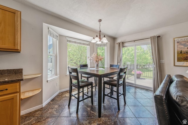 dining space featuring a chandelier, baseboards, and a textured ceiling