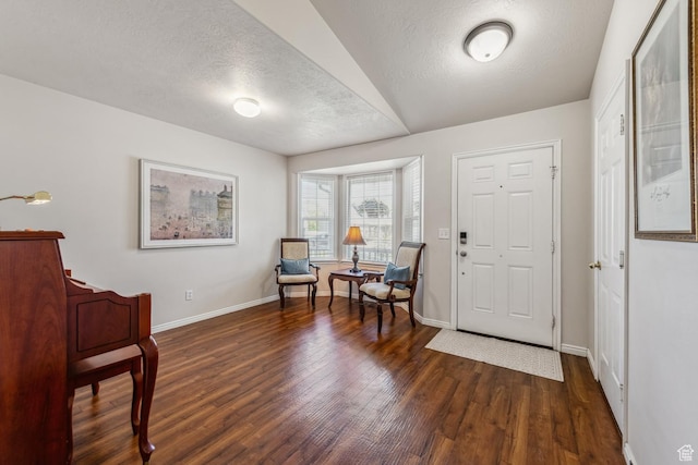 foyer featuring dark wood-type flooring, baseboards, and a textured ceiling