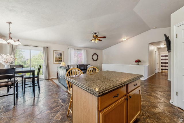 kitchen featuring plenty of natural light, a center island, lofted ceiling, and stone tile floors