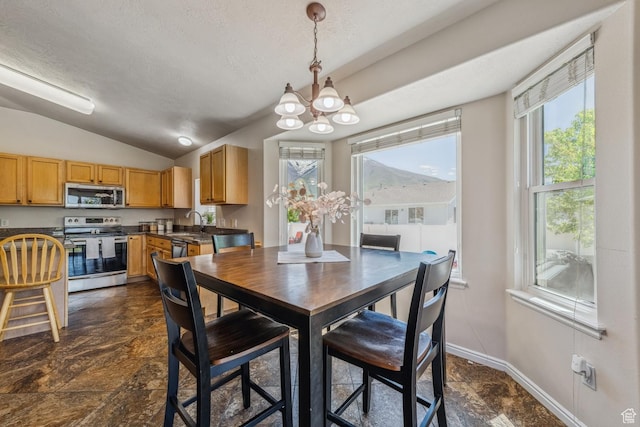 dining area with a chandelier, vaulted ceiling, healthy amount of natural light, a textured ceiling, and dark stone finish flooring