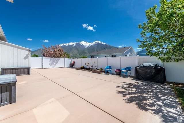 view of patio with a mountain view, a fenced backyard, and grilling area