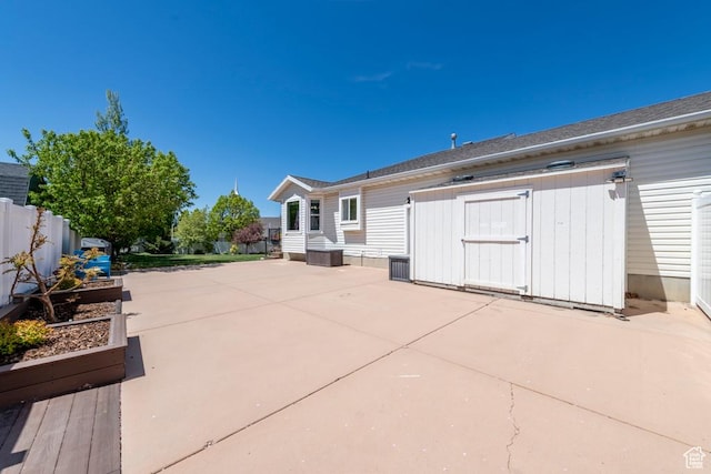 view of patio with a storage unit, an outbuilding, and fence
