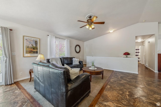 living room with stone tile floors, ceiling fan, vaulted ceiling, and baseboards