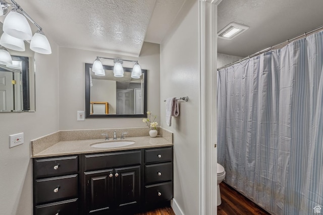 bathroom featuring a textured ceiling, wood finished floors, toilet, vanity, and a shower with shower curtain