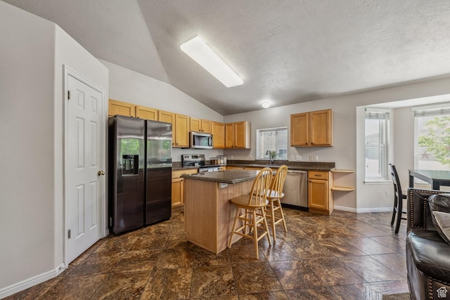 kitchen featuring stainless steel appliances, lofted ceiling, a kitchen island, dark countertops, and baseboards