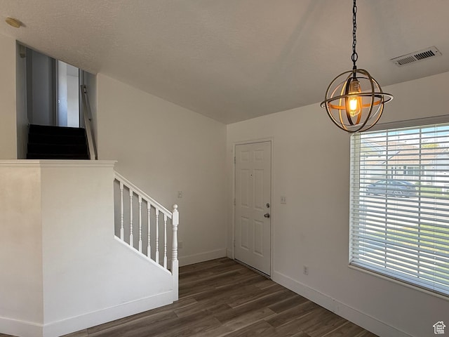 foyer featuring stairs, dark wood-style flooring, baseboards, and a chandelier