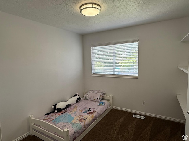 bedroom with a textured ceiling, baseboards, and dark carpet