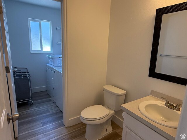 bathroom featuring washing machine and clothes dryer, vanity, wood finished floors, toilet, and baseboards