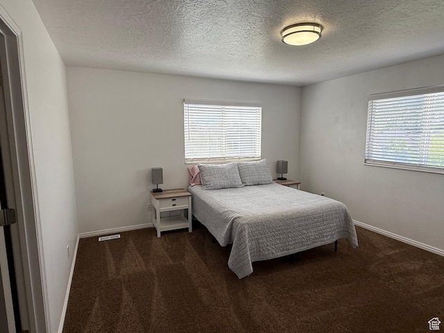 bedroom with carpet, a textured ceiling, and baseboards