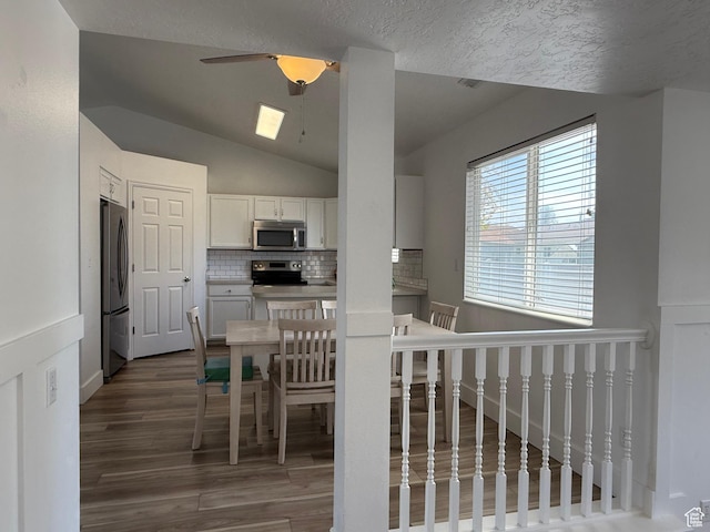 kitchen with stainless steel appliances, wood finished floors, a ceiling fan, white cabinetry, and tasteful backsplash