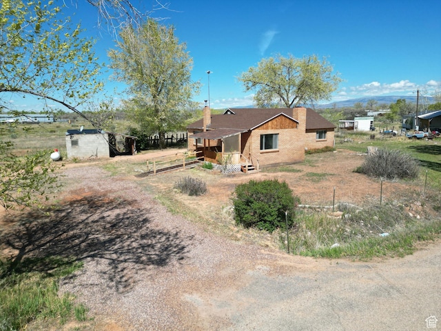 back of house with brick siding and a chimney