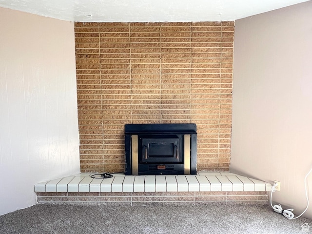 detailed view of carpet flooring and a brick fireplace