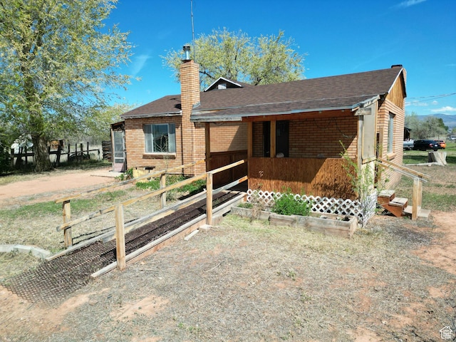 back of property with a chimney, roof with shingles, and brick siding