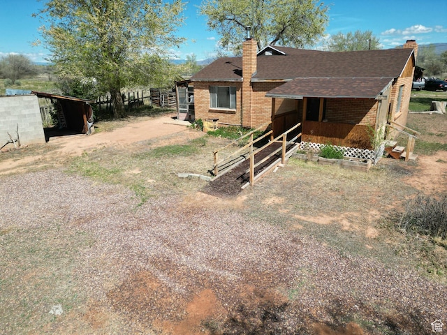 rear view of property with a chimney, a shingled roof, and brick siding