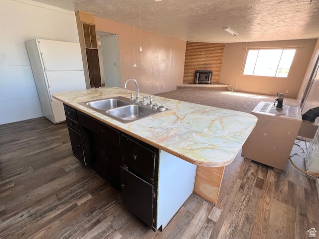 kitchen featuring freestanding refrigerator, a sink, dark wood-style floors, a textured ceiling, and light countertops