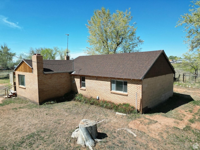 view of property exterior featuring brick siding, a shingled roof, and a chimney