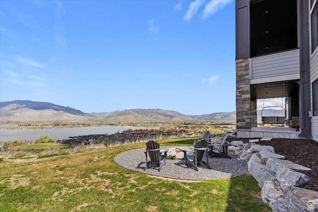 view of green lawn with a fire pit and a water and mountain view