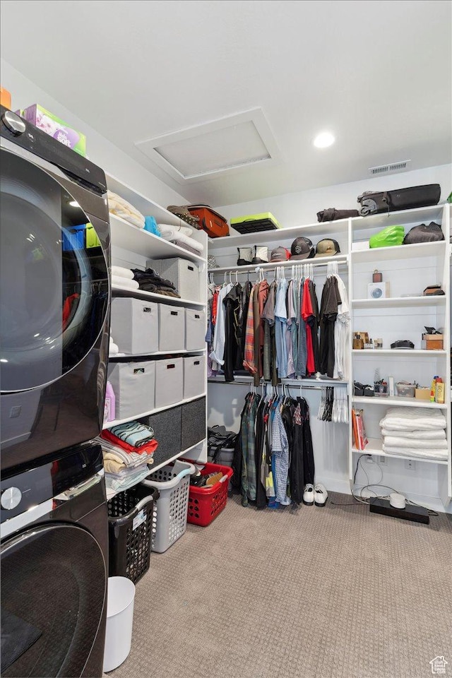 walk in closet with stacked washer / dryer, carpet floors, and attic access