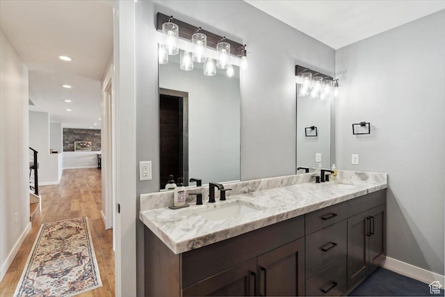 full bath with wood finished floors, double vanity, baseboards, and recessed lighting