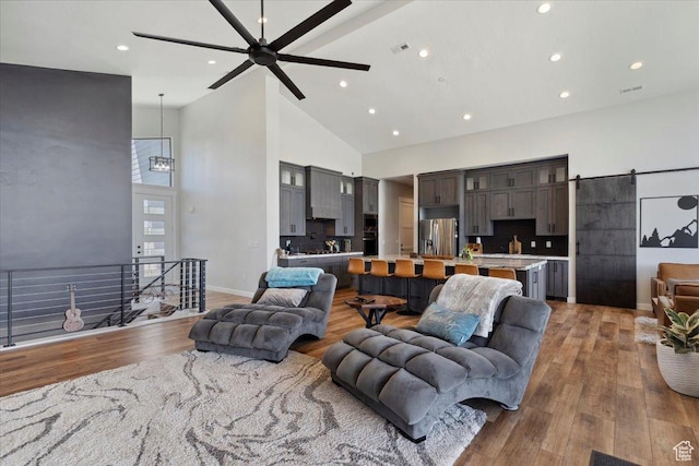 living room with high vaulted ceiling, ceiling fan, recessed lighting, wood finished floors, and a chandelier