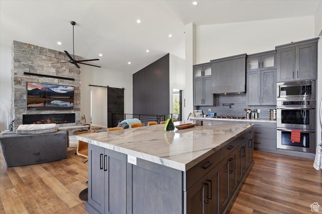 kitchen with a barn door, high vaulted ceiling, open floor plan, ceiling fan, and a kitchen island