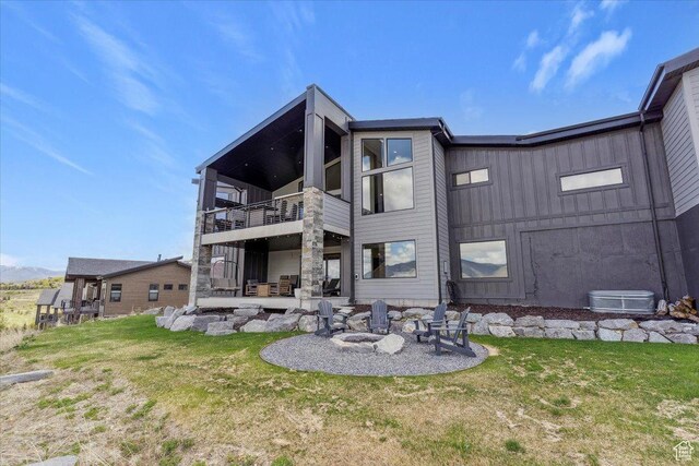 back of house featuring a balcony, an outdoor fire pit, a yard, and a patio area